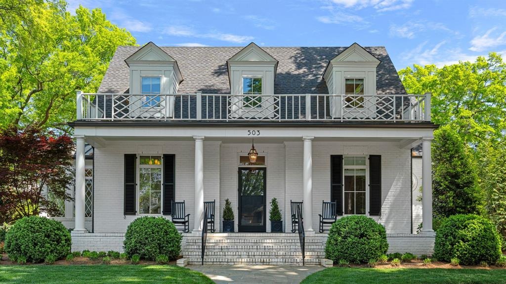White brick colonial home with a double front porch and lattice balcony