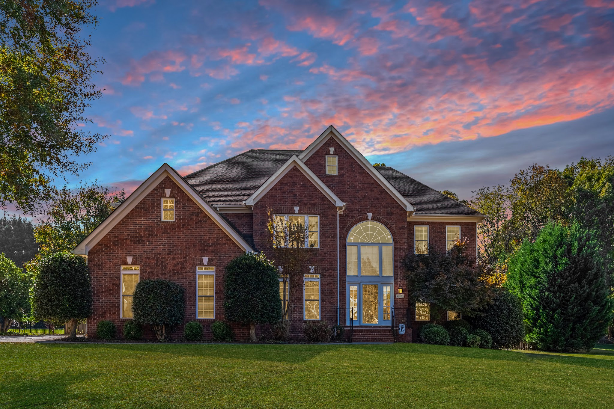 Brick two-story home at dusk under a pink and blue sky